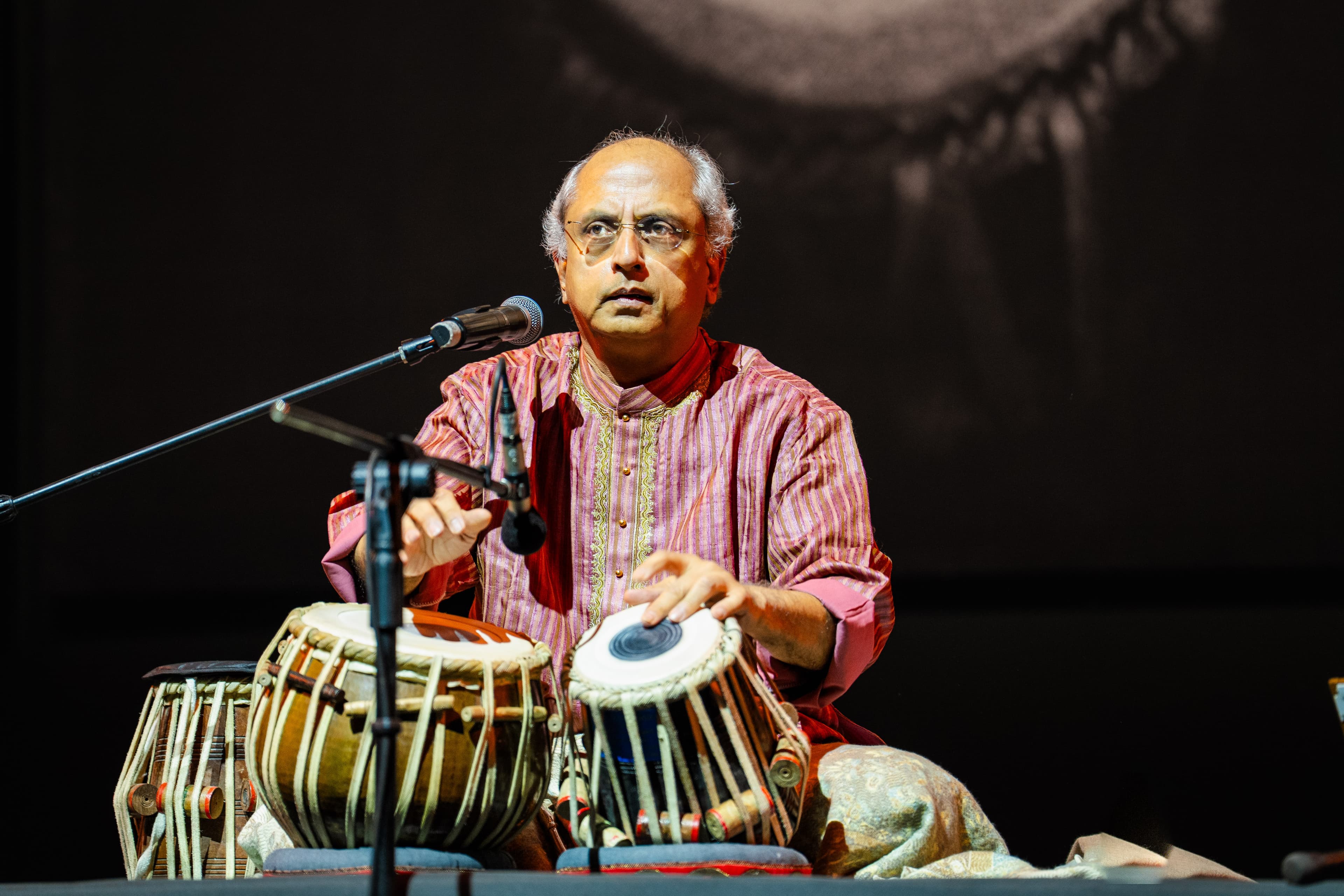 Yogesh Samsi in concert playing tabla in a red kurta